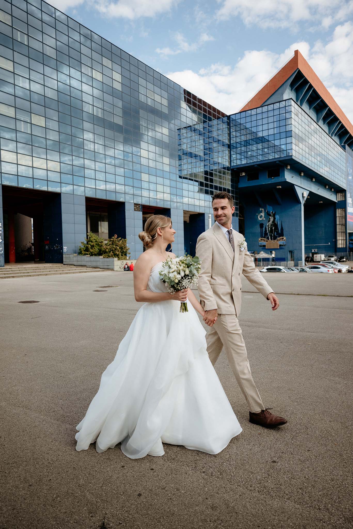 Bride and groom walking in front of Maksimir Stadium in Zagreb after their wedding ceremony.
