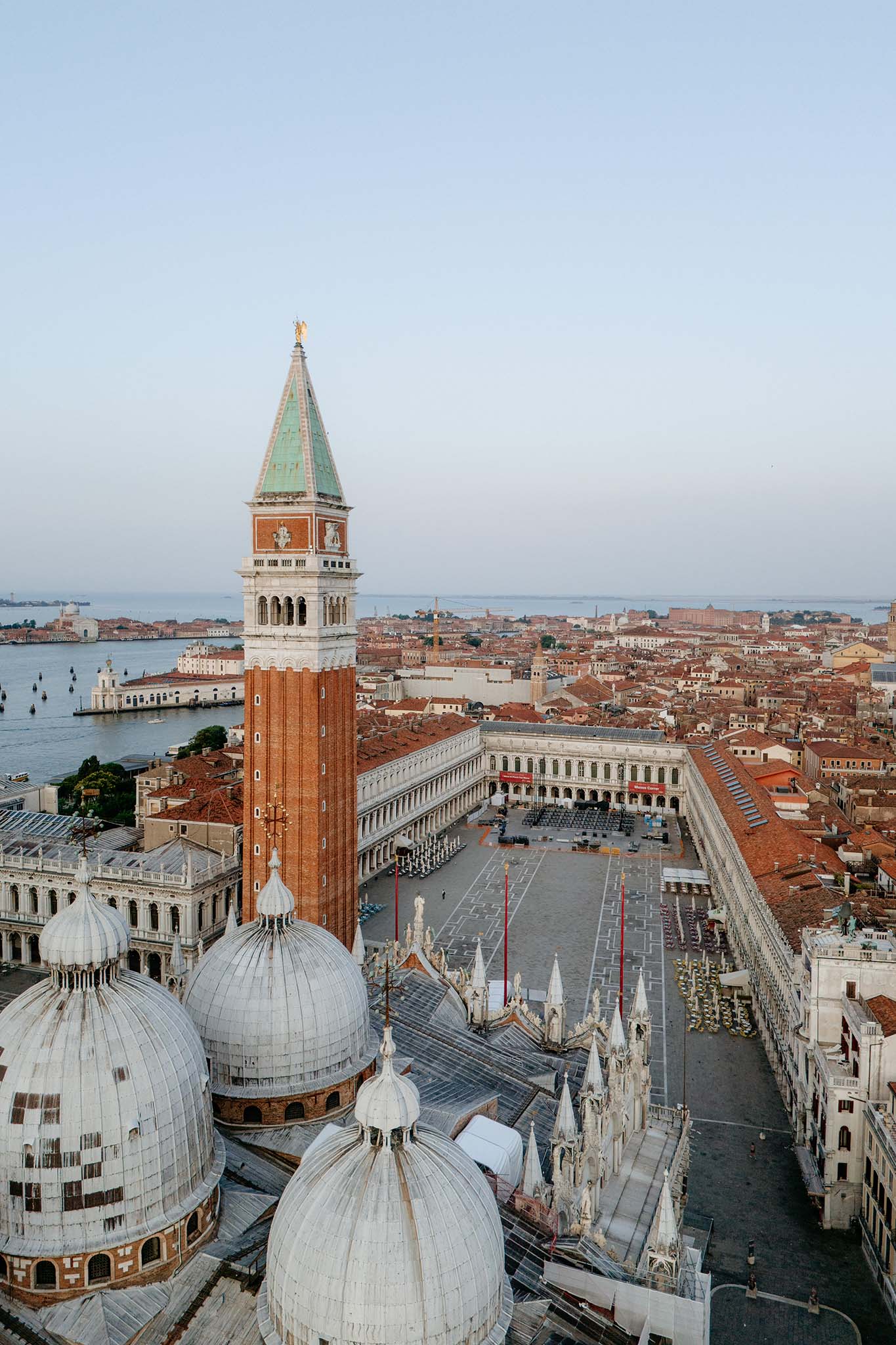 Aerial drone view of St. Mark’s Square in Venice at sunrise, showcasing the basilica, the campanile and surrounding architecture.